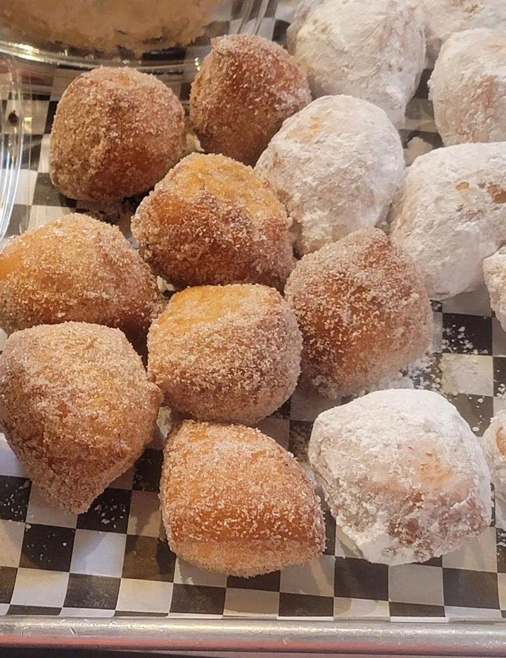 Cinnamon-sugar and powdered-sugar beignets on checkered paper